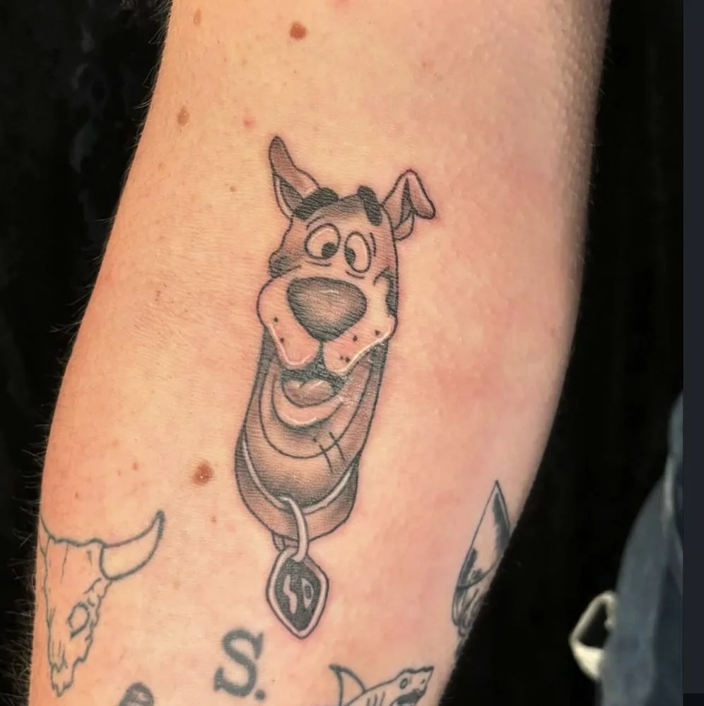 Black-and-grey cartoon dog portrait tattoo