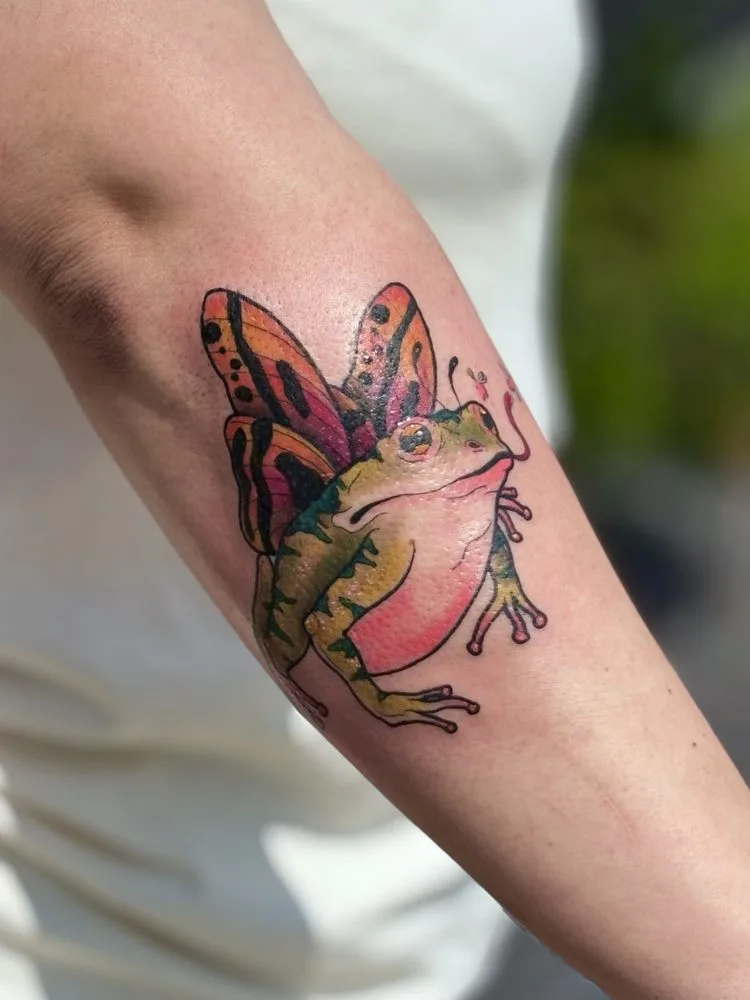Colorful frog with orange and pink butterfly wings, neo-traditional tattoo by Audrey Madeline in Beaumont, TX