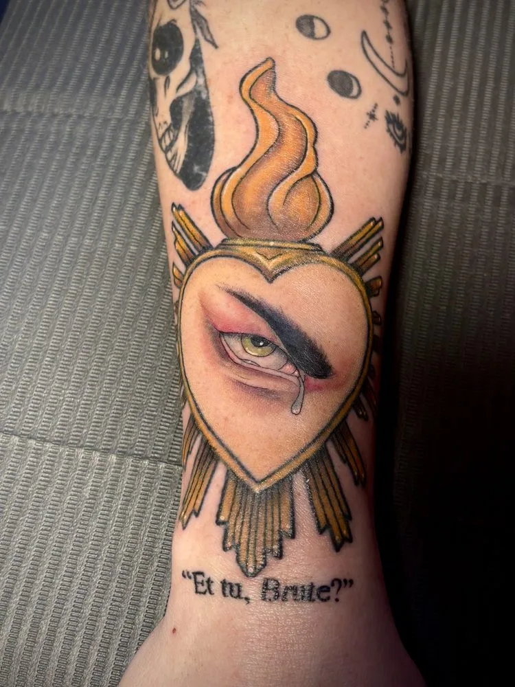 Neo-traditional flaming sacred heart tattoo with golden rays and a realistic crying eye
